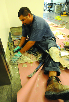 Construction worker Humberto Negrete tears apart the walls to remove the soaked Fiberglas in the Humanities Building