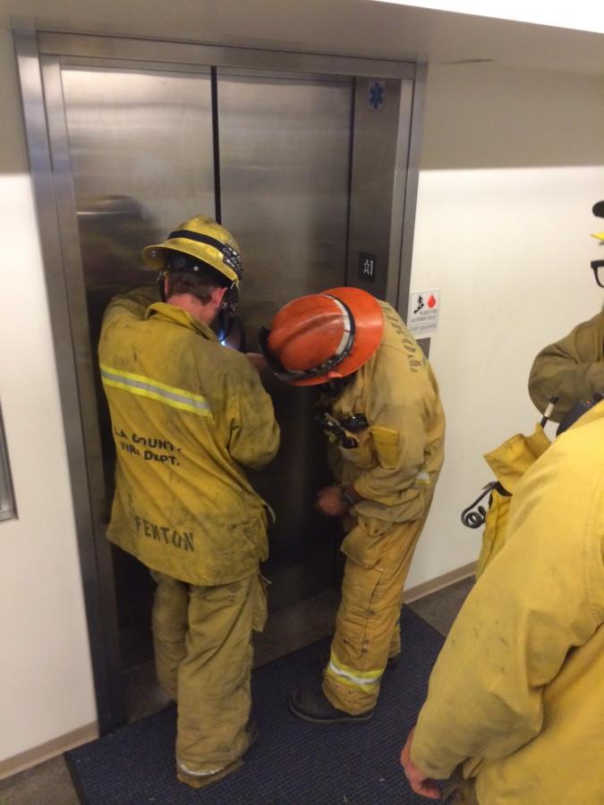 Firefighters work on prying open an elevator where a student was stuck in the Humanities Building.