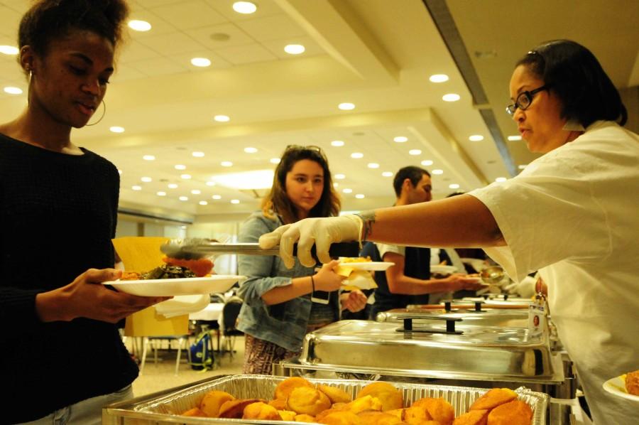 From left to right: Kaylan Green, 20, psychology, and, Lauren Martinez, 19, international relations get served their potion of yams, fried chicken, cabbage, and cornbread on the buffet line at the Taste of Soul Festival held in the East Dining room atop of the bookstore on Feb. 26.