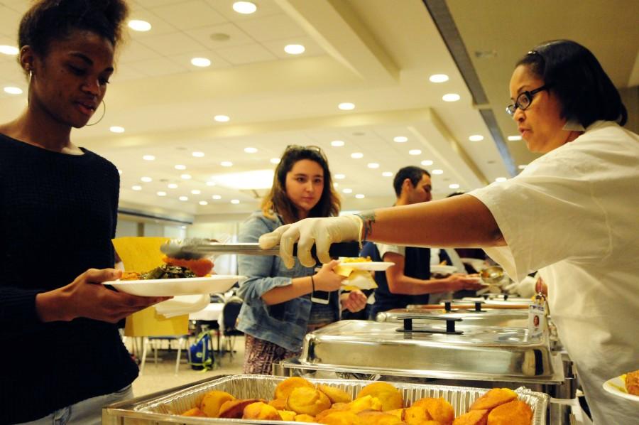 (Left) Kaylan Green, 20, psychology, and, Lauren Martinez, 19, international relations get served their potion of yams, fried chicken, cabbage, and cornbread on the buffet line at the Taste of Soul Festival in the East Dining room atop of the bookstore on Thursday, Feb. 26. Photo credit: Armando Zelaya