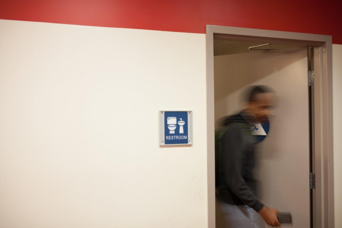 Someone walking out of one of the gender neutral bathrooms on campus, which are labelled restroom. Photo credit: Jorge Villa