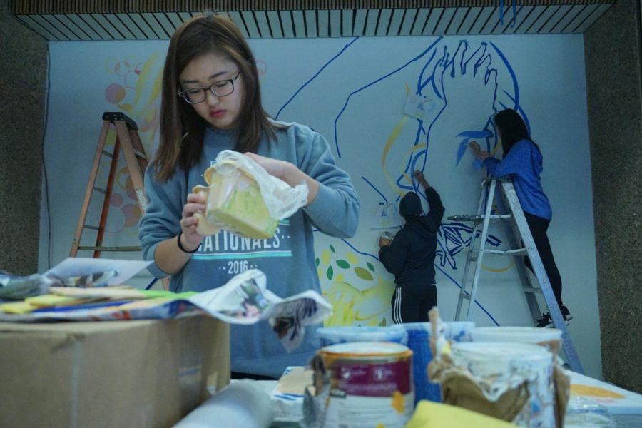 Haruka Kanemura ,19, studio art major, and her team painting a mural in the East Lounge of the Student Activities Center. Photo credit: Ryan Guitare