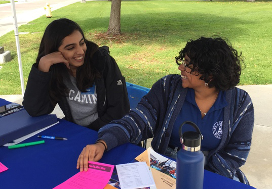 Ambassadors Anam Khan and Jenebrith Pastran chat while waiting for a student to approach them with a question. Photo credit: Faith Petrie