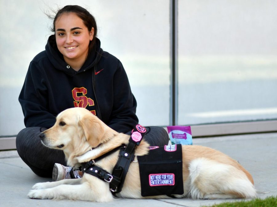 Dani poses with her service dog Luca in front of the Humanities Building. Photo by Jack Kan.