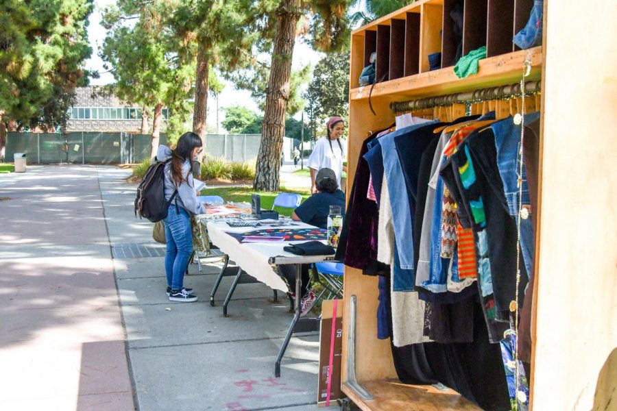 A+student+looks+at+the+various+examples+of+zines+located+on+the+center+table+during+the+Zine+Clubs+Pop-up+Thrift+Store+on+Wednesday%2C+Oct.+16%2C+at+the+El+Camino+Colleges+Library+Lawn.+The+Zine+Club+sold+pins%2C+zines%2C+handcrafted+earrings+and+clothing+redesigned+by+members+of+the+club.+Rosemary+Montalvo%2FThe+Union
