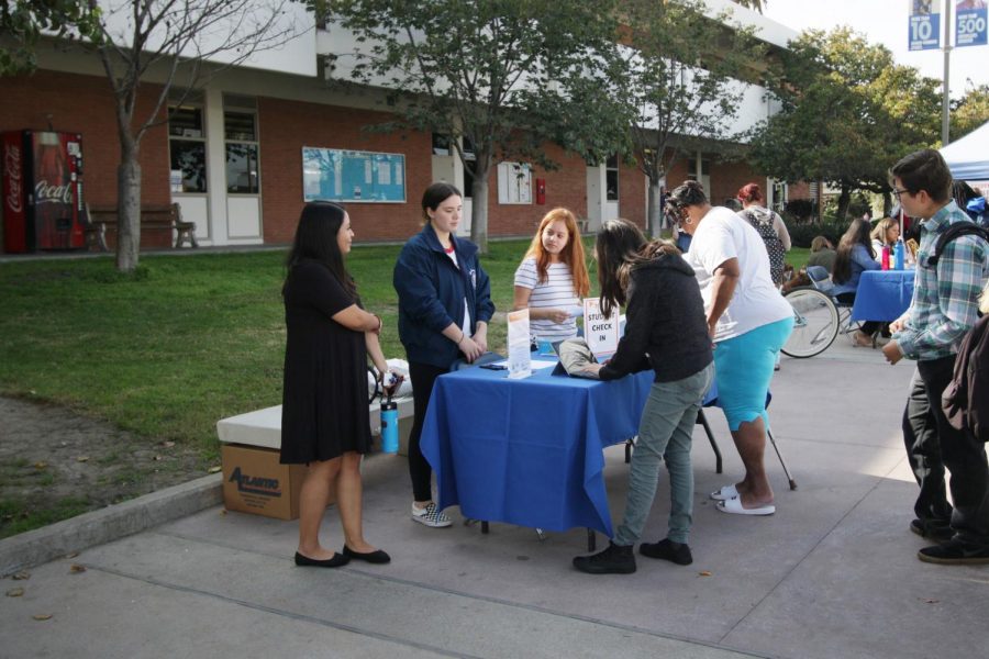 Students line up and sign in to the Harvest Festival near the Student Services Building on Tuesday, Nov.19. They received a paper to fill up with stickers available at the booths they visited during the event. Viridiana Flores/The Union