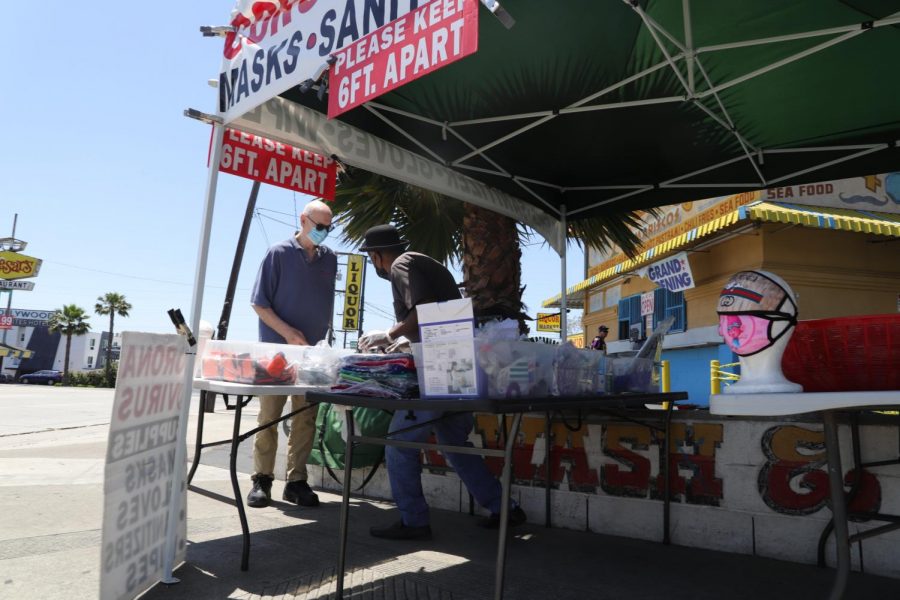 Keith Terry, [right], tends to a customer looking to buy hand sanitizer from his Corona Virus supplies stand, Wednesday, May 13. Keith intends on keeping his stand up until the end of the quarantine in order to provide the community with essentials to protect against the virus. (Rosemary Montalvo / Warrior Life)