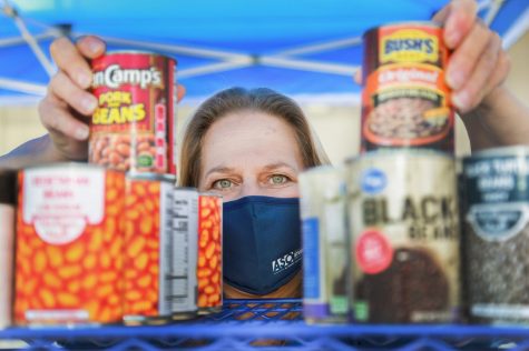 Kim Cameron organizes some of the canned foods, lining them up by type, on Thursday, May 6, in one of the Warrior Pantry tented distribution stations. The food handed out at the Warrior Pantry include a good mix of canned foods and fresh produce. (Mari Inagaki/ Warrior Life)