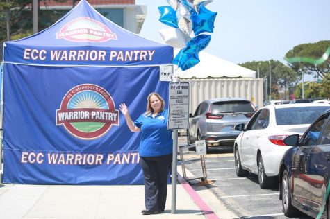 As cars line up to receive food and other supplies from the Warrior Pantry, Kim Cameron takes a moment to pose next to one of the balloon decorations she set up for the Warrior Pantry on Thursday, May 6. (Mari Inagaki/ Warrior Life)