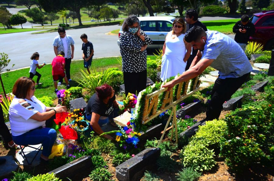 Family and friends gather around Juan Carlos Hernandez's grave where Jose Guadalupe Hernandez, far right, attaches a floral bouquet with his son's name to the tombstone where some of his ashes are buried at the Holy Cross Catholic Cemetery in Culver City. Photo by Jose Tobar/The Union