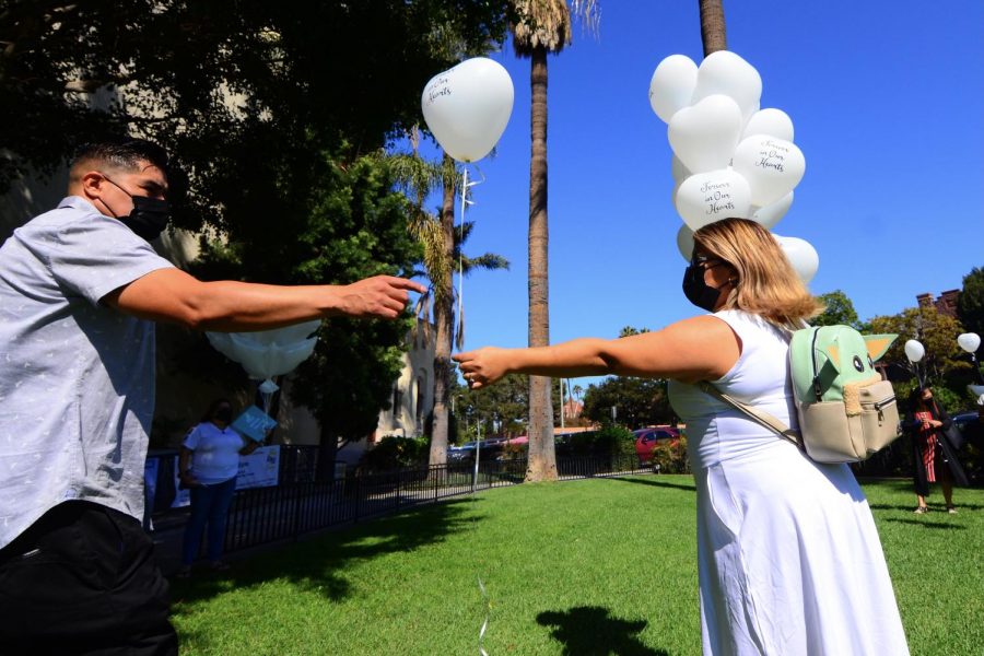 Juan Carlos Hernandezs father, Jose Guadalupe Hernandez, takes a balloon from Stephanie Pineda on the lawn of the Saint Vincent de Paul Parish in Los Angeles. The balloons with the inscription Forever in Our Hearts will be released in a symbolical gesture honoring his memory outside the church grounds. Photo by Jose Tobar/The Union Photo credit: Jose Tobar