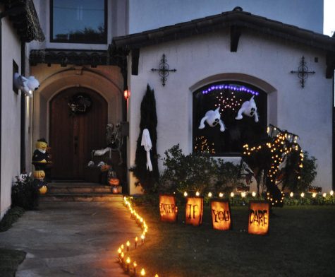The entrance is illuminated as a welcoming factor but when you pay close attention there are skeleton decorations and plenty of carved pumpkins with spooky faces. On the side of the entrance a sign that says "Enter If You Dare" lighted up with some outdoor ghost decorations hanging on top on Monday, Oct. 25 in the Redondo Beach area. Photo by Isabella Villatoro/The Union.