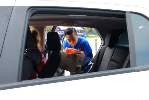 El Camino student success coach David Ruiz, 27, loads a box of free food gifts into a car driven by a community member during an ECC Veterans Day and Community Thanksgiving event.  Photo by Jose Tobar/Ittihad