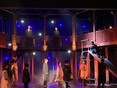 (L) Adult Man played by Thomas Evans and (R) Adult Woman played by Therese Rico stand on the balcony. The cast of Spring Awakening on the stage with Otto played by Eric Lazaro on the slide and Ernst played by Ivan Orozco in the center of the stage as they sing "The Word of Your Body Reprise" following the scene when Hanshcan played by Elijah Villongco and Ernst confess their feelings for each other.