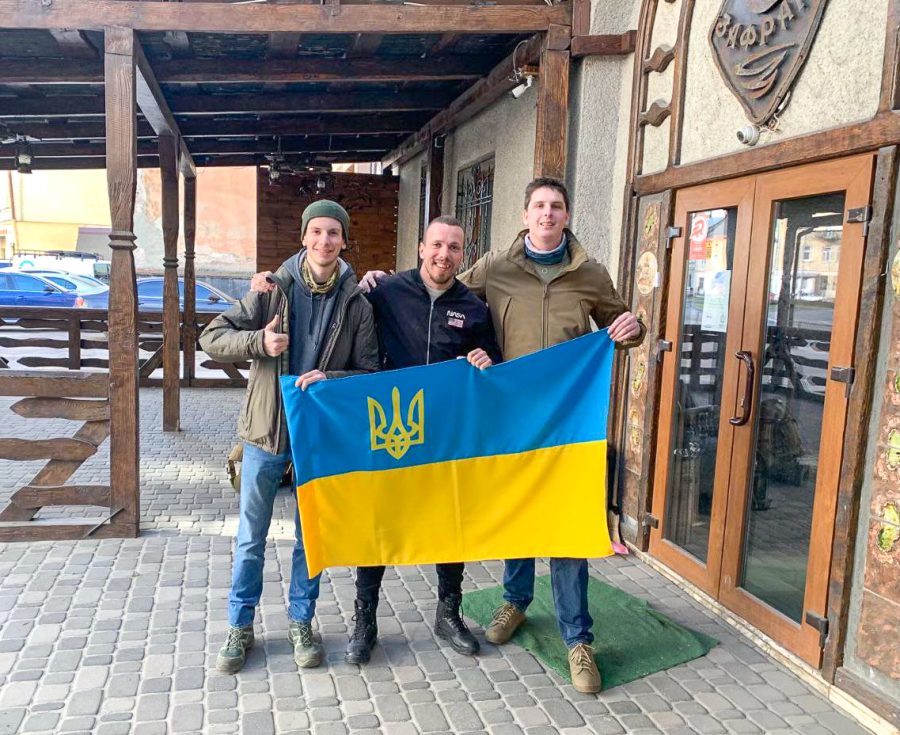 Will Hogan (right) holds up a Ukrainian flag with other volunteers in Lviv, Ukraine, on Tuesday, March 22. Hogan volunteered in a medical tent and as a combat medic in the Ukrainian Foreign Legion. Photo courtesy of Will Hogan