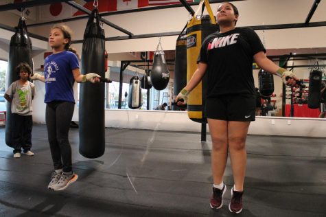 Abby Osorio, 9, (L) and Amy Plancarte, 11, jump rope as part of their boxing conditioning as Reian Davis, 11, looks on at Sweet Science Boxing & MMA Gym in Hawthorne, Calif. on Thursday, April 7, 2022. They are members of a boxing club that provides youth a safe and welcoming place to gain boxing classes, one-on-one coaching and opportunities to compete. (Kim McGill | Warrior Life)