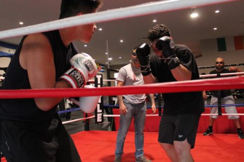 Andy Bocanegra, 15, (L) of Compton, Calif. spars with David Lopez, 15, of Hawthorne, Calif. at Sweet Science Boxing & MMA Gym in Hawthorne on Thursday, April 7, 2022 while David’s coach, Albert Ugarte (center) and Andy’s coach Luis G. (far right) look on. “I hope to become the best by training a lot and sacrificing to get better,” David says. On May 22, the gym hosted a tournament that several boxers here hoped would be their first opportunity to compete. (Kim McGill | Warrior Life)