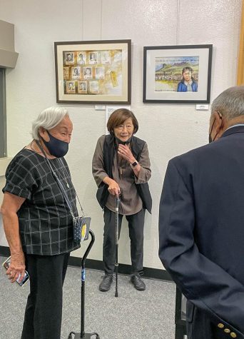 American concentration camp survivor Ruby Mochidome is seen next to a painting of her as a child in the camps. This was during the reception and showcasing of the art in the El Camino Library on Oct. 13. (Ash Hallas | The Union)