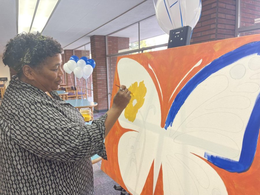 Lillian Justice, El Camino College Registrar, contributes to the painting of a monarch butterfly - the symbol of migrants throughout the Americas during the opening of the UndocuWarriors art exhibition on Oct. 24 located in Schauerman Librarys Collaboration Room. (Kim McGill | The Union)