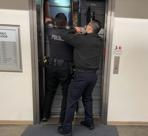 Patrol Officers Francisco Esquela and Benjamin Kim attempt to pry open the elevator and free a trapped student in the Humanities Building on March 16. (Joshua Flores | The Union)