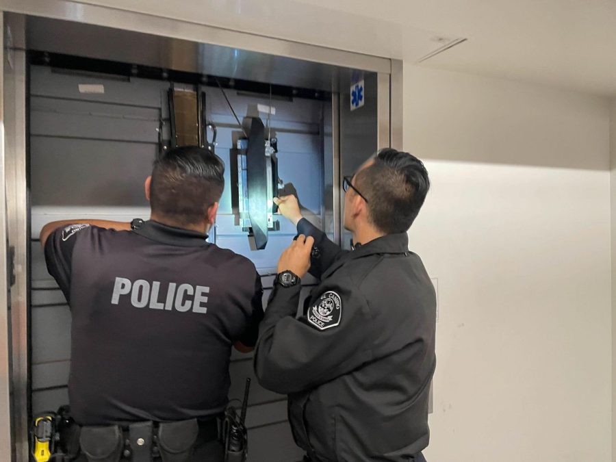 El Camino Patrol Officers Francisco Esqueda and Benjamin Kim inspect an elevator that went down in the Humanities Building for ways to open it on March 16. (Joshua Flores | The Union)