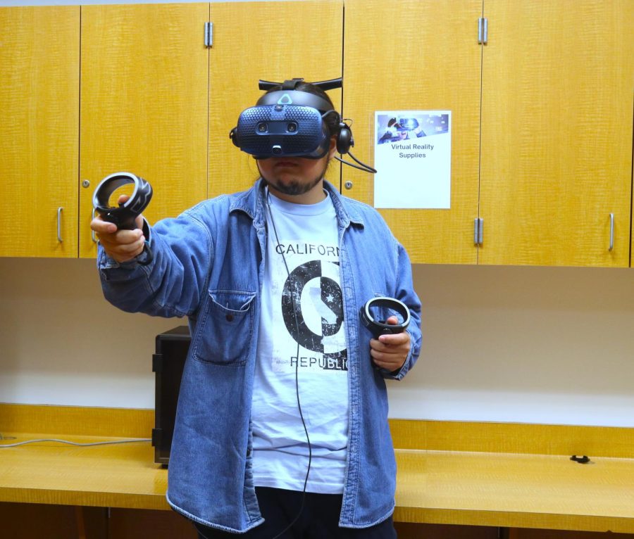 Library Media Technician Steve Dao wears the virtual reality set in the Makerspace on March 22. Dao said he is completely blind when he puts the set on. (Anthony Lipari | The Union)