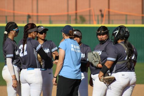 The El Camino College Warriors huddle with head coach Jessica Rapoza (center) in the seventh inning, after a final score from Pasadena City College Lancers first baseman Marcella Ordonez, on an RBI from third baseman Jaimie Harris, on Thursday, April 6, at the ECC Softball Field in Torrance. The Warriors defeated the Lancers 9-3. (Elsa Rosales | The Union)
