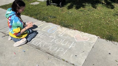 Alison Rafters, 20-year-old interclub council representative for the Child Development Club, draws on the floor with chalk that says, "Welcome to the "You & Me Play Group!" on Saturday, April 18.