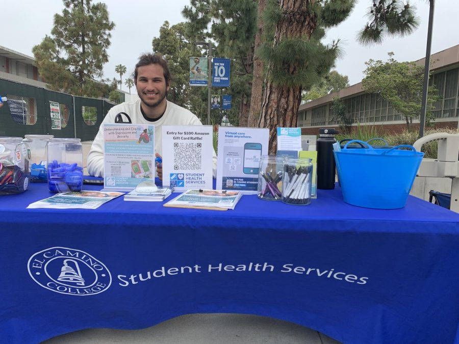 Student Health Ambassador Gabriel Cunha, 26, promotes the Student Health Services at the Health Center on May 25. The stand offered hand sanitizers, lip balms, condoms and flyers promoting TimelyCare and workshops. (Igor Colonno | The Union)
