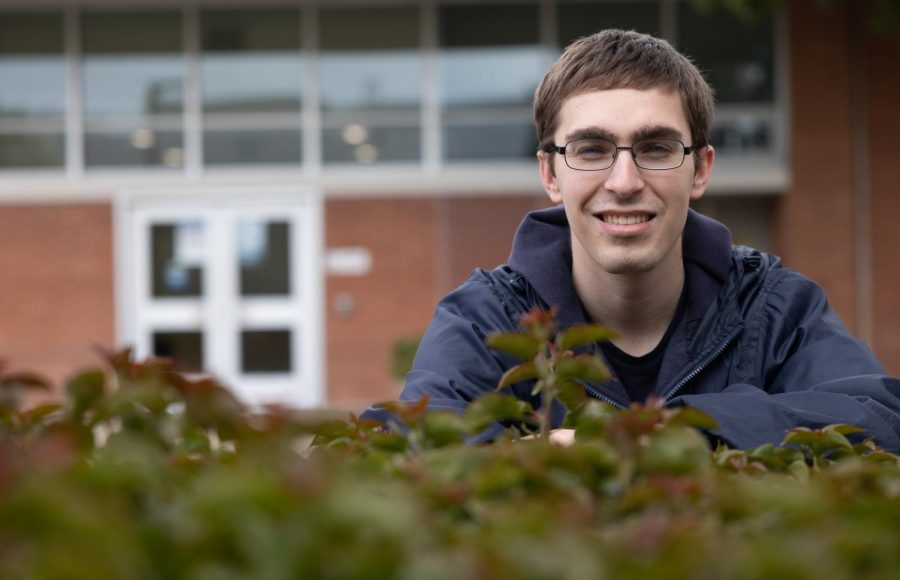 Music major Anthony Lipari leans over a shrub in the Chemistry Courtyard on March 22. Lipari joins a select group of students being awarded the Presidential Scholarship for the Spring 2023 semester. (Khoury Williams | The Union)