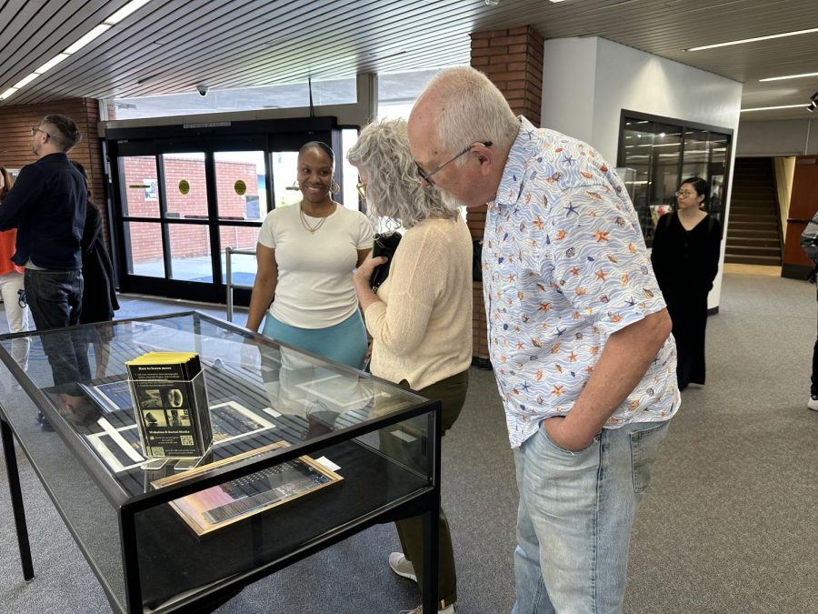 Photography student Yolanda Flowers (left) discussing her photos in a display case with two attendees of the Traces Photography Exhibition on Thursday, April 27. Flowers said one comment she gets about her photos is people asking “How do you get your shots?” (Eddy Cermeno | The Union)