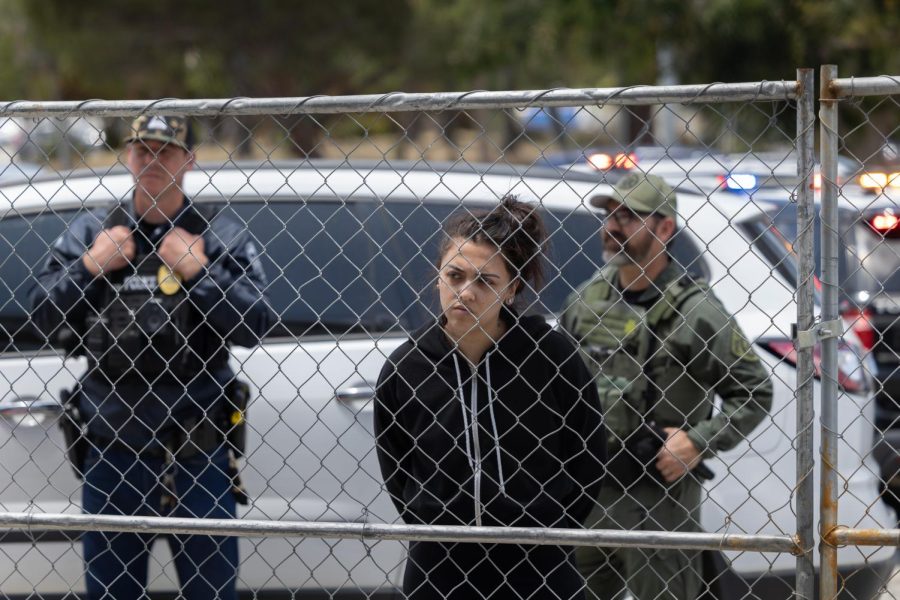 A worker from the Torrance Green Room stands handcuffed as police raid the illegal dispensary on Thursday, June 8. The dispensary has been running its illegal operations outside of El Camino College since early this year. (Ethan Cohen | The Union)