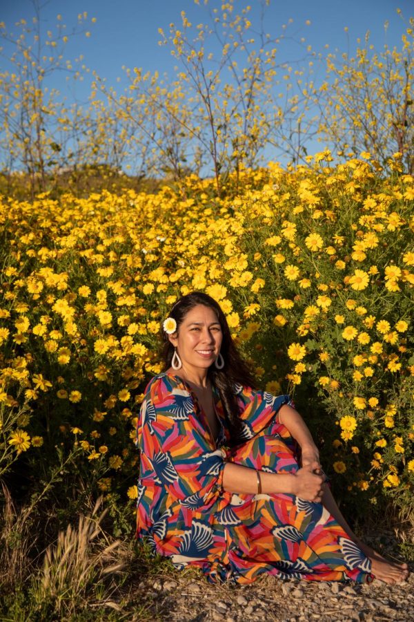 Monica Delgado sits in front of the yellow flowers near White Point Beach in San Pedro on Sunday, May 7. Delgado wears a colorful dress to symbolize the multiple cultures she has and embraces. (Ash Hallas | Warrior Life)