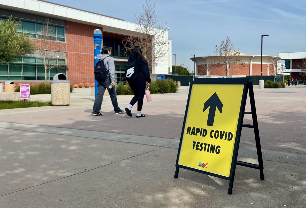 Two students walk past a sign advertising the free on campus rapid COVID testing offered in room 205 of the Communications Building at El Camino College, on February 16. The testing site is still open this fall semester from Monday-Thursday and is free of charge to El Camino students and employees. (Delfino Camacho | The Union)