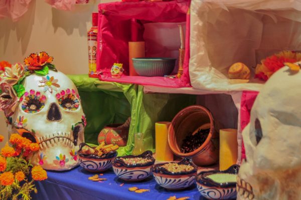On the main altar of the Dia De Los Muertos exhibit, there are bowls filled with edible items such as coffee with cinnamon sticks, beans, grain, and rice which are offerings all meant to symbolize remembrance and care for those who have died. (Isabelle Ibarra| The Union)
