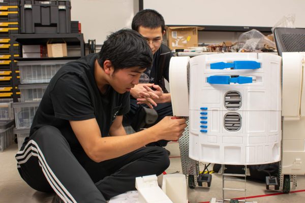 Jason Irie, left, and Joshua Molina rework the arm part of R2-D2 for the final finishing touches to prepare for the Dec. 6 robotics exhibition on Tuesday, Dec. 5. (Misaki Asaba | The Union)