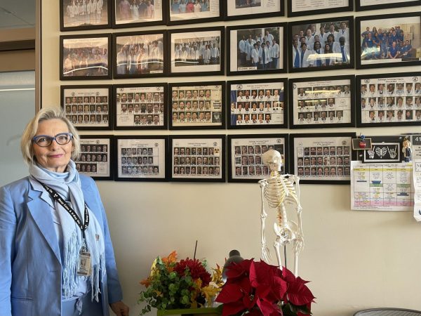 Dawn Charman, radiologic technology program director and coordinator, standing in front of her office wall. The wall is covered in framed photographs of her previous students.