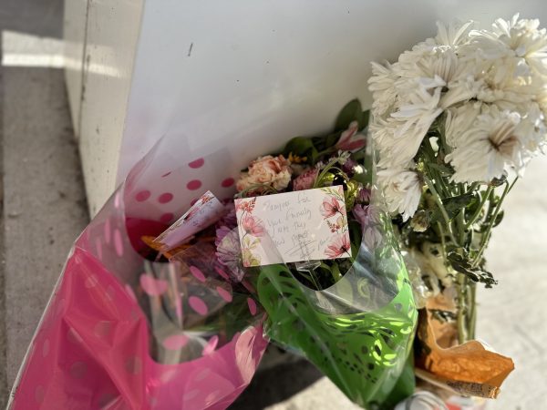 The candles and bouquets of flowers rest by the pillar of the Gymnasium where the attack on Junko Hanafusa happened on Sunday, Dec. 24, 2023. An unsigned note in one of the bouquets reads: “Prayers for your family. May they find peace.” (Ma. Gisela Ordenes | The Union)