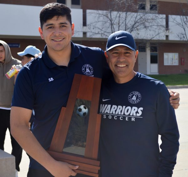 El Camino College men's soccer coach Michael Jacobson, right, and assistant coach Steven Barrera pose with the state championship trophy on Thursday, Feb. 15, during the championship parade. (Caleb Smith | The Union)