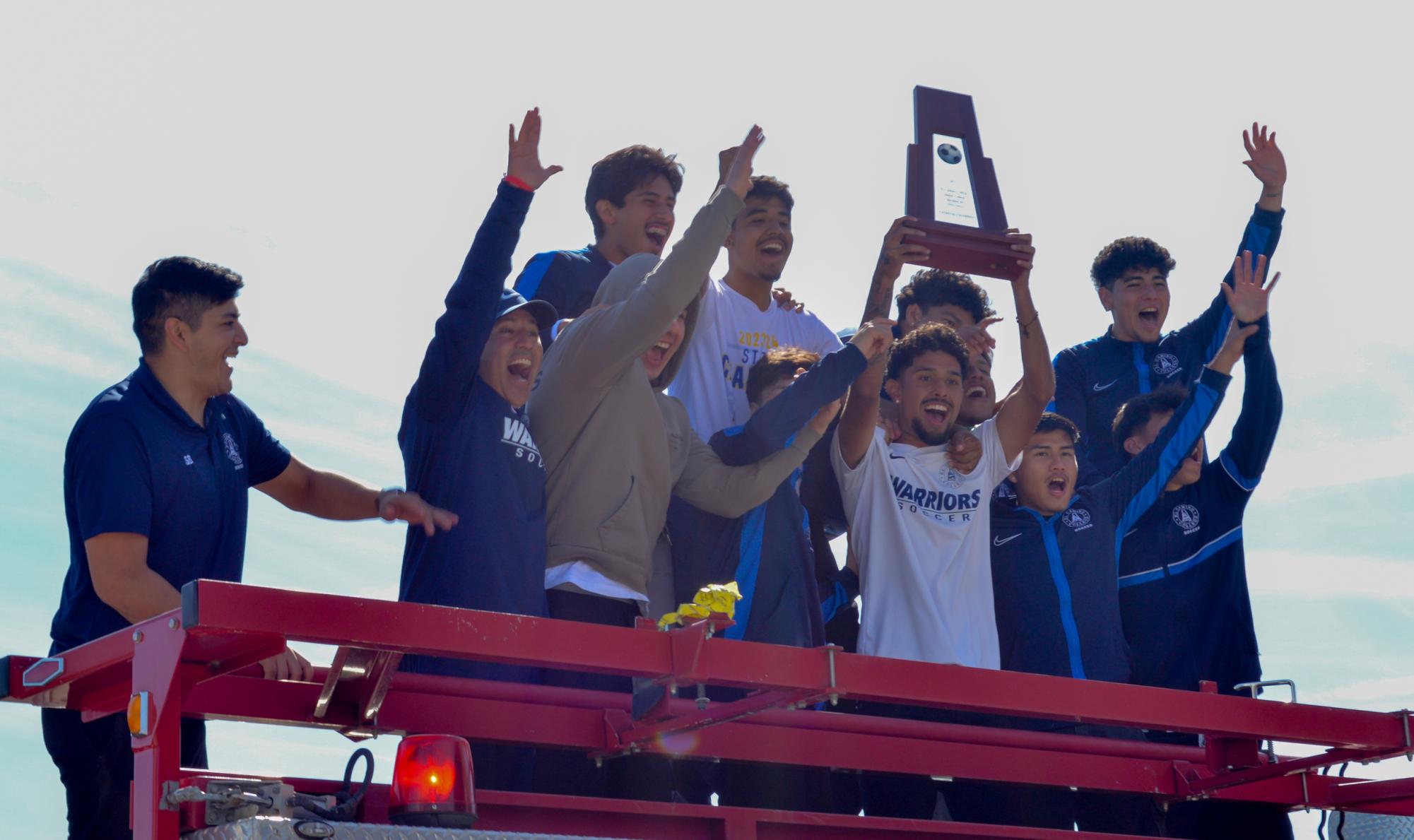 Players from El Camino Colleges national and state championship-winning soccer team celebrate as they hold up the state championship trophy on Thursday, Feb. 15, during the championship parade held on campus. (Caleb Smith | The Union)