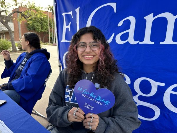 Sam Vargas, 19, who studies business and finance, volunteers at the Student Services booth on Wednesday, Feb. 14. She holds a heart-shaped fan that she gives out to those who seek assistance from their tent. (Ma. Gisela Ordenes | The Union)