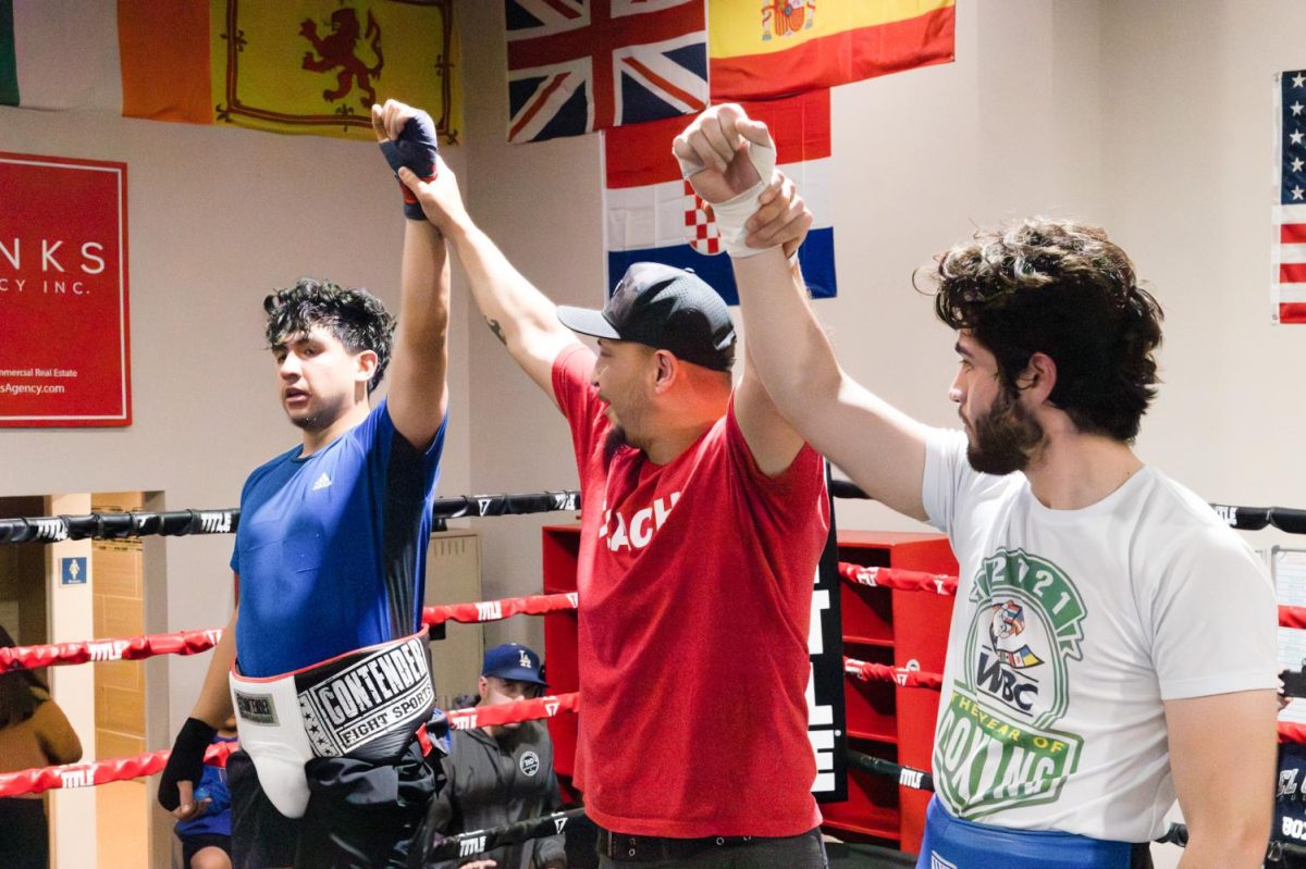 Sweet Science Boxing and MMA gym owner Marco Trejo, middle, lifts up Francisco Chavarin, left, and Ricardo Mercado after their battle at El Camino College’s first “Fight Night” event in Hawthorne on Saturday, May 20, 2023. (Khoury Williams | The Union)