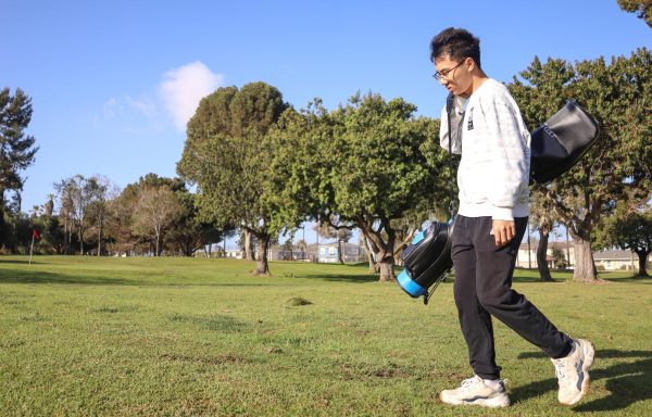 Economics major Haozhe Sun, 21, perches his golf bag on his shoulder as he walks on the green during his Tuesday golf classes at the Alondra Park Golf Course. While El Camino College offers clubs and bags to golf students, Sun brings his own clubs to class. (Delfino Camacho | The Union)