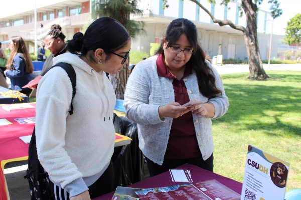 Sociology major Michelle Vrado, 21, left, gets transfer information from Juana Reyes, California State University, Dominguez Hills graduate admissions coordinator, during the El Camino College Transfer Center's Spring University Fair on Thursday, March 21 on the ECC Library Lawn. ECC is the No. 1 California community college in transfers to CSUDH. (Elsa Rosales | The Union)