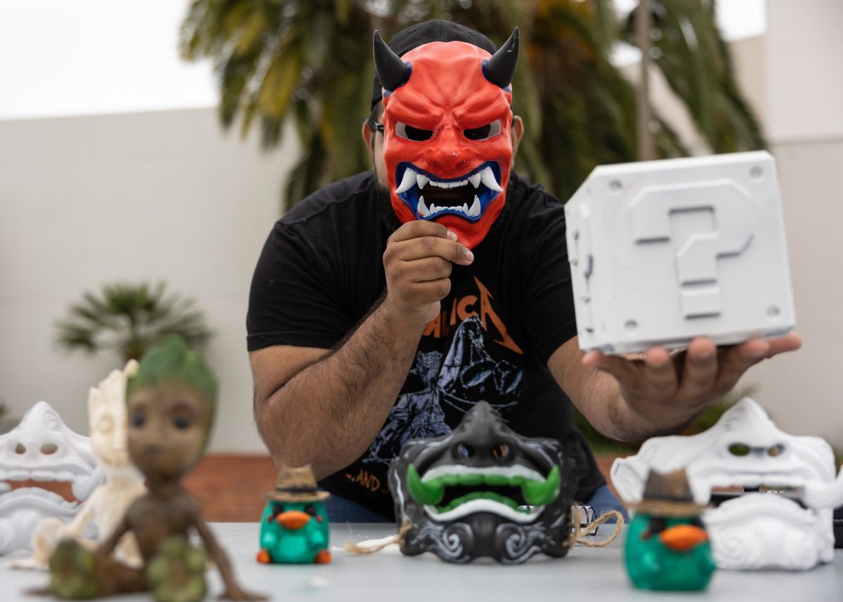 Christopher Pizarro, a 19-year-old chemistry student, stares through a Japanese-style oni mask and presents a Question Block from Super Mario at the Maker's Fair on Monday, April 22. Pizarro recently got into designing and painting 3D-printed items, which he sold at the event. “Designing stuff online and then bringing it to life, that’s pretty incredible,
