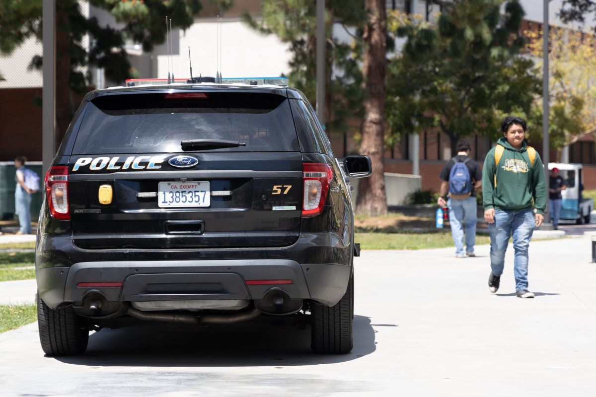A student walks past a police car next to the Math Business Alliance Building on Wednesday, April 17. (Raphael Richardson | The Union)