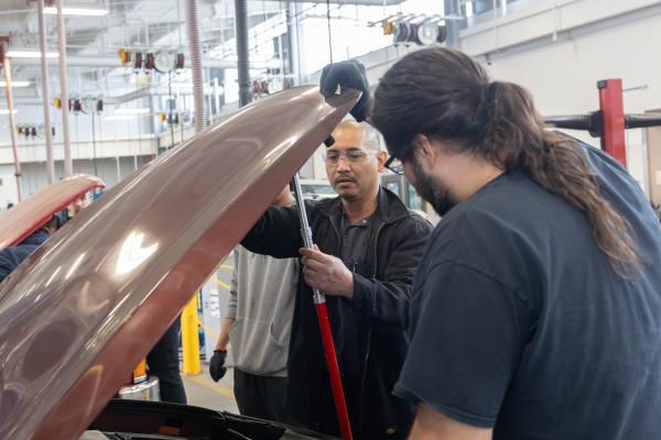 Jeremy Duque, an automotive technology instructor, shows a student how to hold the hood of a car open during a lab class on Saturday, April 20 in the Center of Applied Technology work area. (Warrior Life | Greg Fontanilla)