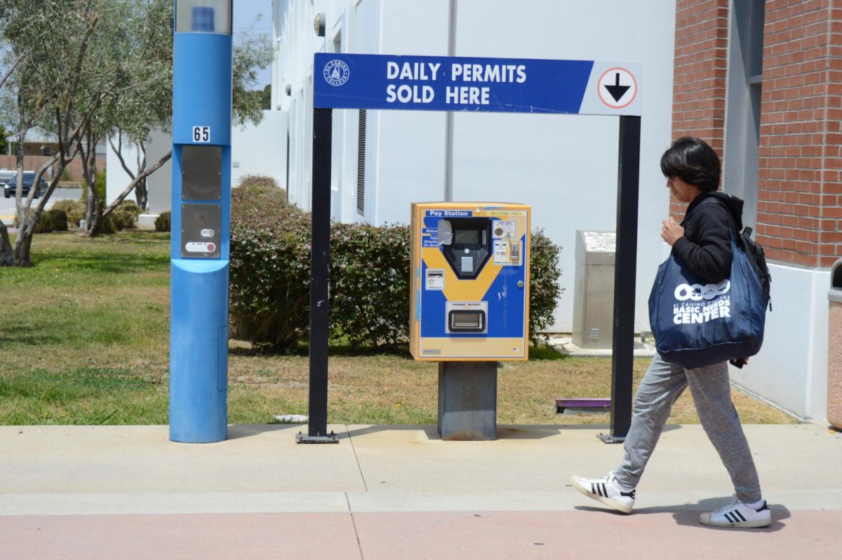 An El Camino College student walks past a parking permit machine located outside of parking Lot C on Wednesday, May 22. The Board of Trustees approved the reinstatement of parking permits for El Camino students and employees during its meeting on Monday, May 20. (Clarence Davis | The Union)