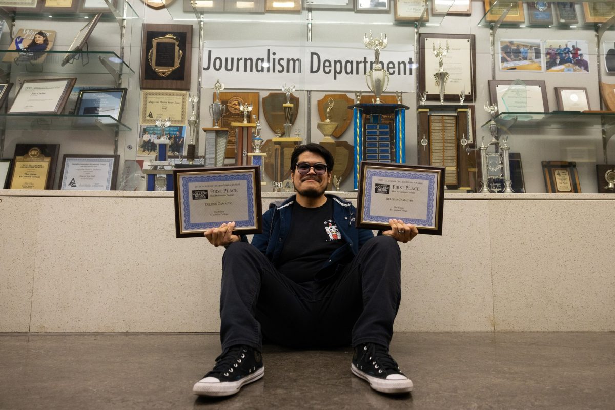 Former Union Editor-in-Chief Delfino Camacho holds up his first-place award plaques in front of the journalism department trophy case in the Humanities Building at El Camino College on Wednesday, April 17. Camacho won multiple awards, including first place in Best Headline Portfolio and Multimedia Package. “Even when I’m gone and graduated, I left a little bit of my mark here just like everyone else did,” he said. (Ethan Cohen | The Union)