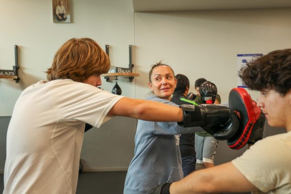 El Camino College's boxing instructor and boxing club advisor, Rachel Pittock, center, demonstrates proper form with a student on March 21. (Monroe Morrow | The Union)